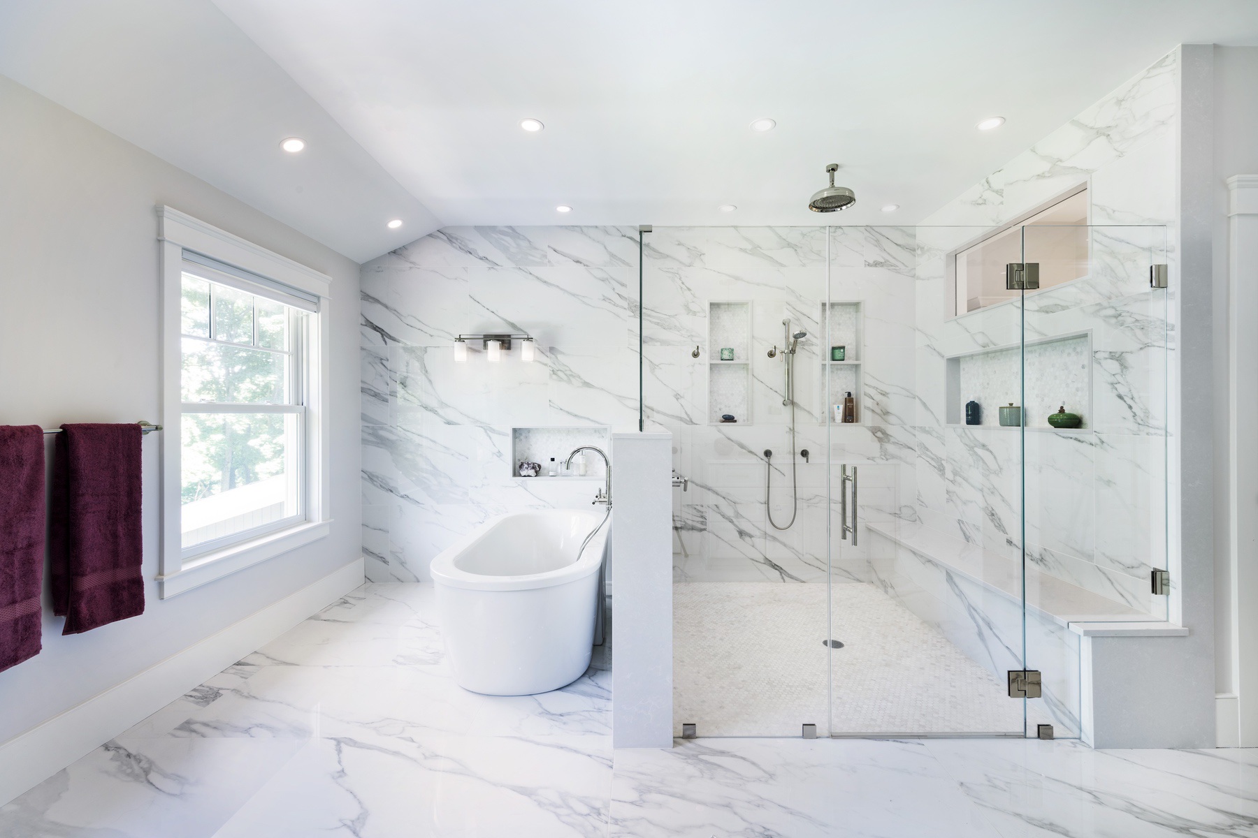 Primary bathroom with white marble tile, freestanding tub and large frameless glass walk-in shower